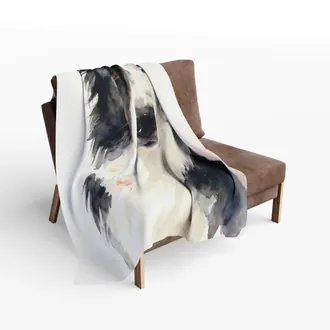 Fleece blanket with a watercolor dog portrait draped over a brown armchair